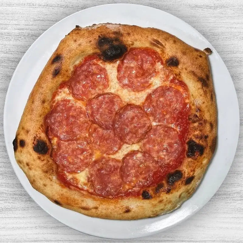 Pizza z salami na drewnianym stole